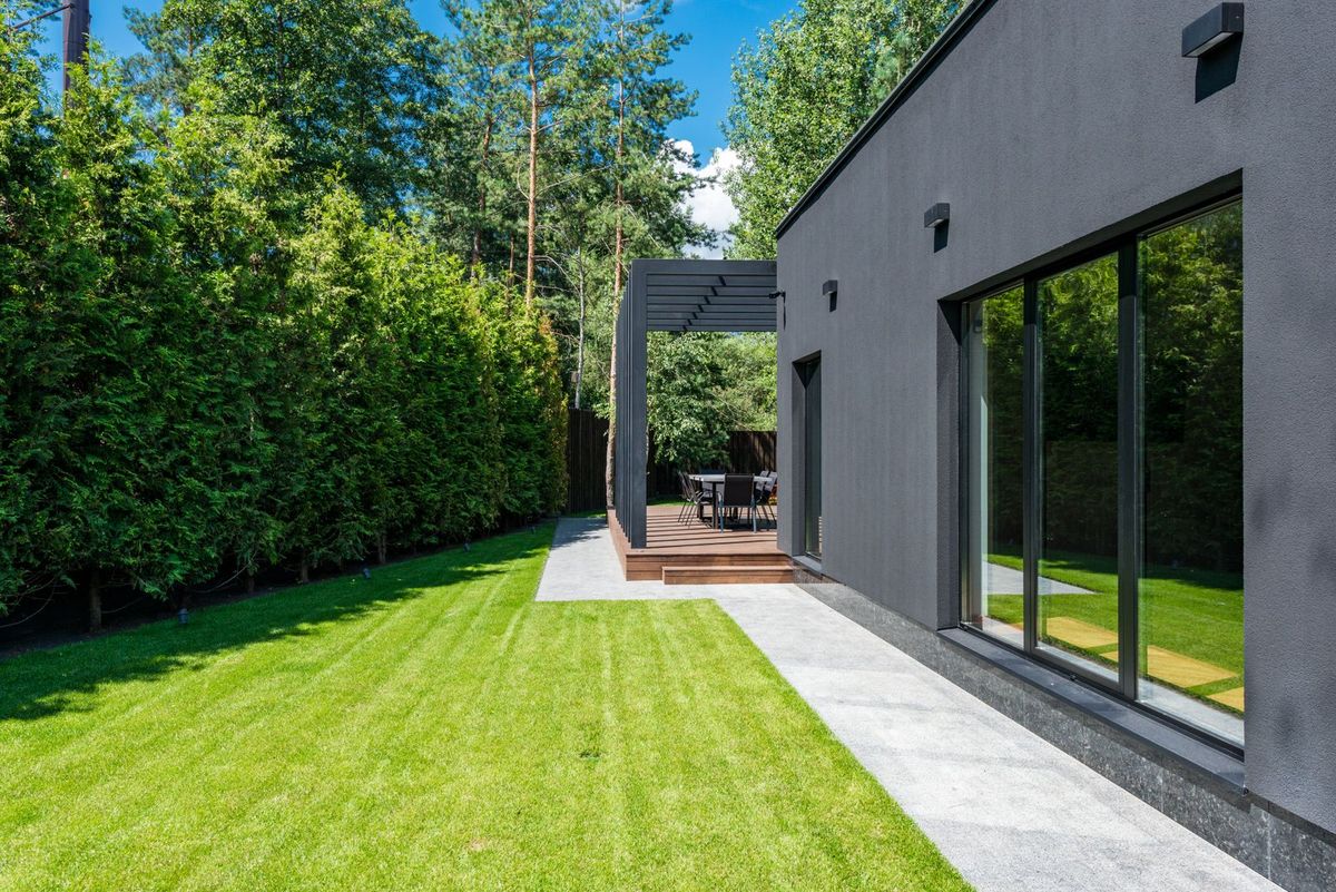Modern backyard with clean concrete walkway and lawn