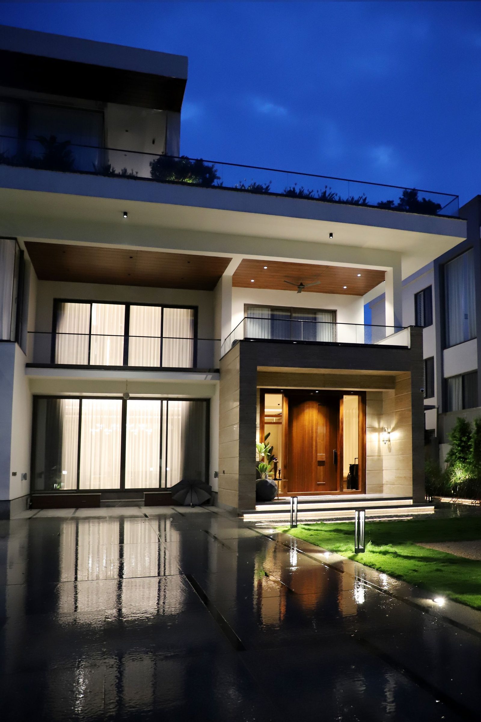 Modern home at night with a spotless, freshly washed driveway reflecting the lights